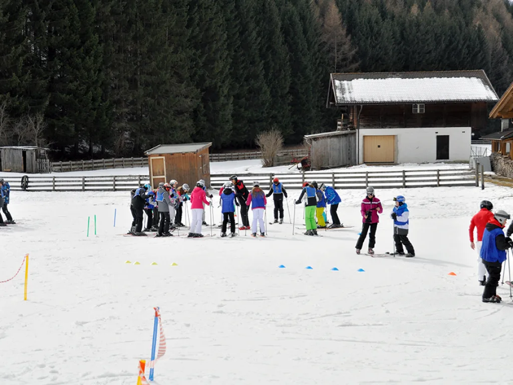 Skigruppen sammeln sich auf der Übungswiese vor einem Stadel.